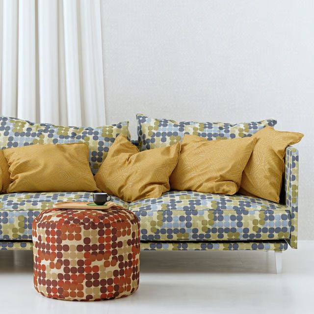 3D product render of a sofa in dotted multicolor upholstery with mustard pillows — same 3D model, different fabric variant generated without reshooting